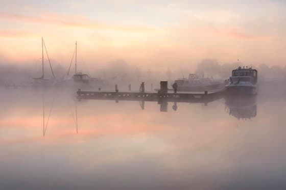 Voor zonsopkomst met mistbanken over de haven.