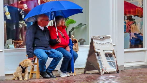 Regen,onder paraplu op een bankje