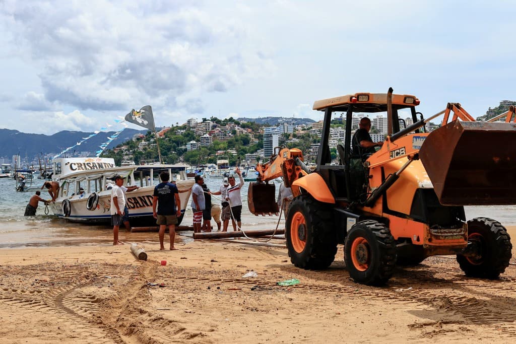 Uit voorzorg wordt in de Mexicaanse badplaats Acapulco een boot uit het water gehaald.