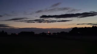 Lichtende nachtwolken boven Steenwijk, met daarbij zichtbaar de verlichte Steenwijker kerktoren, met daarboven de maan, en daarboven een ster of planeet