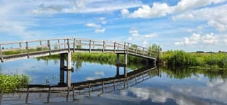 Blauw bewolkte lucht en weerspiegeling in het water 