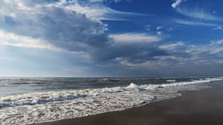 Wolken, zon en rollende golven 