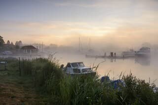 Voor zonsopkomst met mistbanken over de haven.