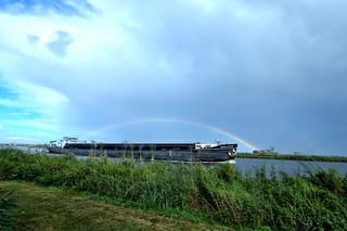 Regenboog boven vrachtschip