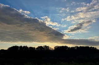Achter een flinke wolk schijnt een nog jonge zon