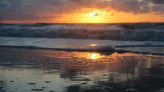 Ruwe zee en donkere wolken bij zonsondergang