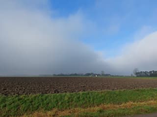 De mist breekt open boven de Waddenkust. Links boven de velden de lage bewolking nog!