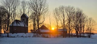 Stralende zon boven het besneeuwde kerkje in Jouswier 