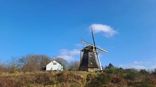 Molen bij blauwe lucht en enkele wolken 