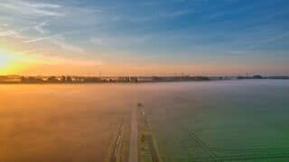 Even na zonsopkomst, ochtenddauw over de landerijen.