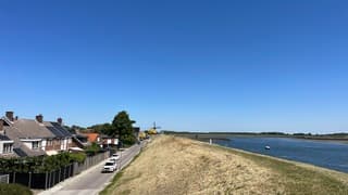 Dorp in de zon onder strakblauwe hemel achter de zeedijk 