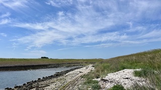 Inham in de Oosterschelde met het badstrandje in de punt , onder lucht met  mooie wolkenstructuren 
