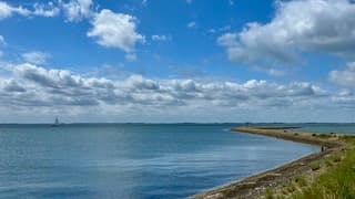 Baan zonlicht vanachter de witte wolken over de Oosterschelde 