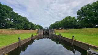 Brug dubbele sluis in Reutum, spiegelbeeld stapelwolken/bomen in het water