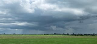 Donkere regenwolken en regen boven de Groninger landerijen 