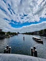 Wolken breken voor de zon boven de Amstel.
