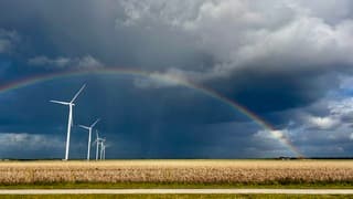 Regenboog en dreigende lucht bij windmolens 