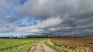 Dreigende lucht en zon; het blijft droog op het gladde landweggetje
