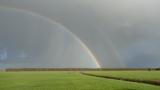 Regenboog met hagel sluiers 