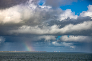 Stukje regenboog onder bui uit boven Texel
