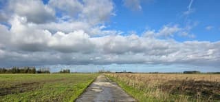 Blauw bewolkte lucht en zon boven de Groninger landerijen 