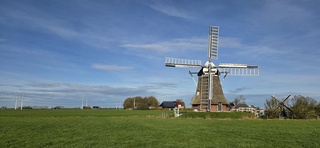 Blauw bewolkte lucht en zon boven de Groninger landerijen 