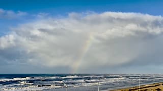 Regenboog in hagelbui aan zee 