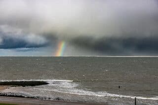 Bui met regenboog boven zee 
