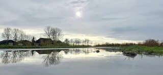 Zon bewolking en weerspiegeling in een regenplas 