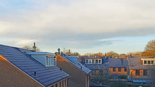 Zon, wolken en witte daken.