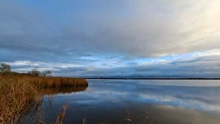Buienwolken weerspiegeld in het water bij het riet van het Schutsloterwijde bij Belt-Schutsloot, tijdstip foto 15.15 uur