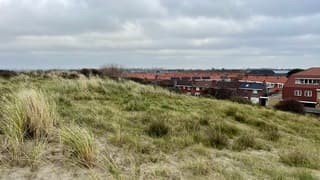 Dorpje achter de duinen met in de verte de skyline van Den Haag