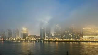 Ondergaande Supermaan  boven de wolkenkrabbers in de mist 