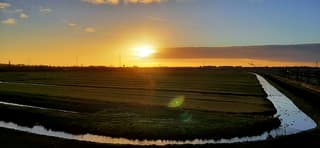 ONDERGAANDE ZON ACHTER WOLKENVELD BOVEN DE ALBLASSERWAAARD 