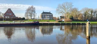 Blauw bewolkte lucht en zon boven het Reitdiep in Garnwerd 