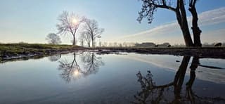 Zon blauwe lucht en weerspiegeling in een regenplas 