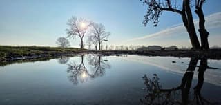 Zon blauwe lucht en weerspiegeling in een regenplas 