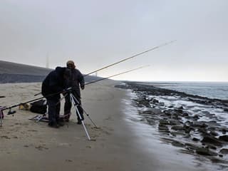 Vuurtoren verdwijnt in de mist,links. De mannen,dik aangekleed ..