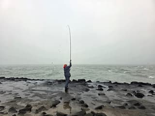 Mistig,grijs,koude wind aan zee..bootje nog net zichtbaar in de mist