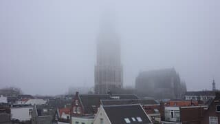 Domtoren verdwijnt in de mist en laaghangende bewolking 
