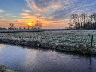 Zonsopkomst en ijslaagje op het water