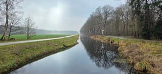 Zon in de wolken en weerspiegeling in het water bij Een