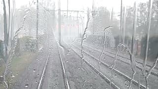 De regen stuift achter de trein in Tilburg 
