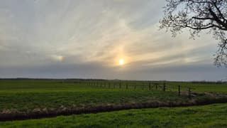 Wolkenlucht met zon en bijzon