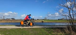 Blauw bewolkte lucht en zon boven fietsers bij Aduard 