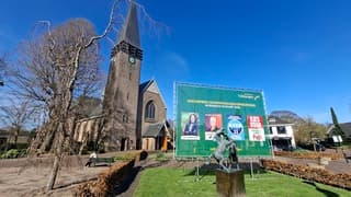 Worstelend paarden voor verkiezingsdagbord en kerk onder blauwe lucht