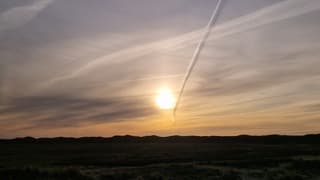Vliegtuigstreep met schaduw boven Texel 