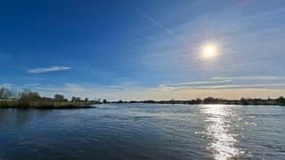 Stralende zon boven een kolkende IJssel