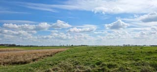 Blauw bewolkte lucht en zon boven de Groninger landerijen 
