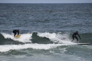 Wolken, zon en veel wind, surfers aan het werk